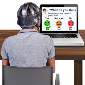A person wearing a helmet sitting at a desk with a computer